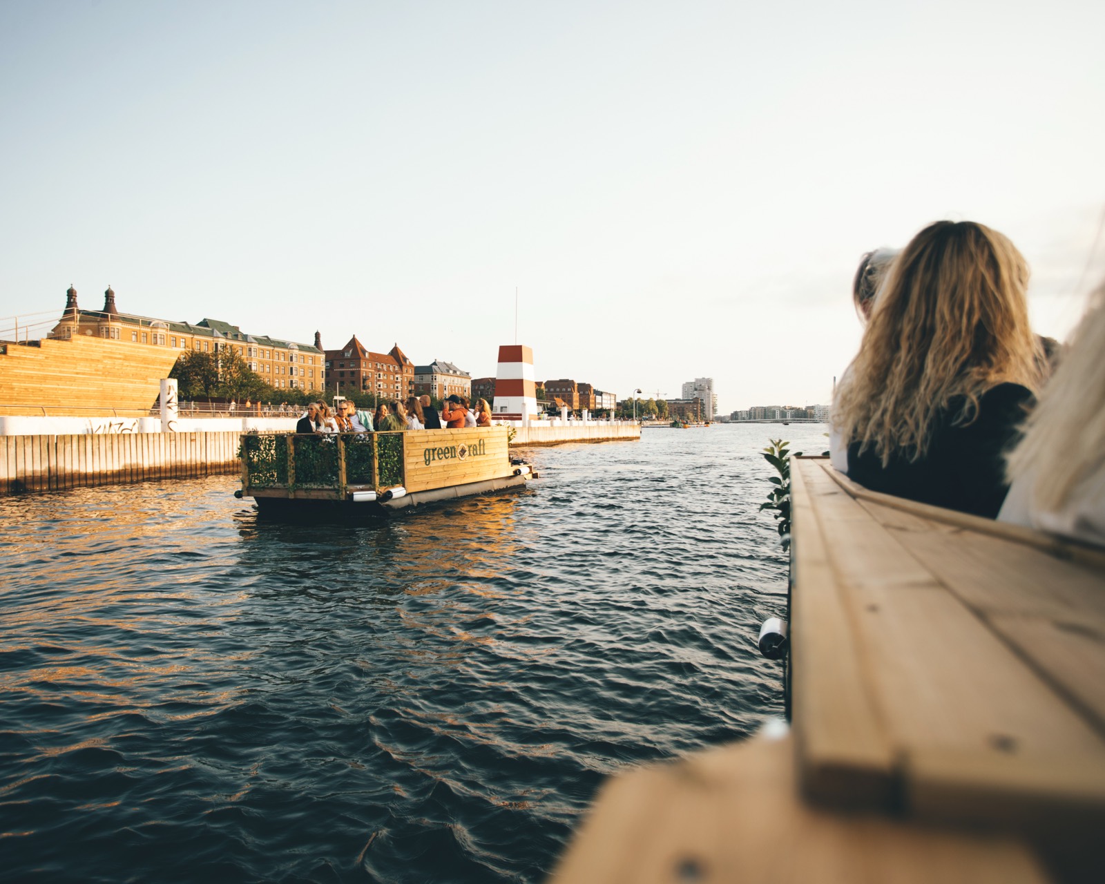 En Green Raft-tømmerflåde sejler forbi en badezone i havnen