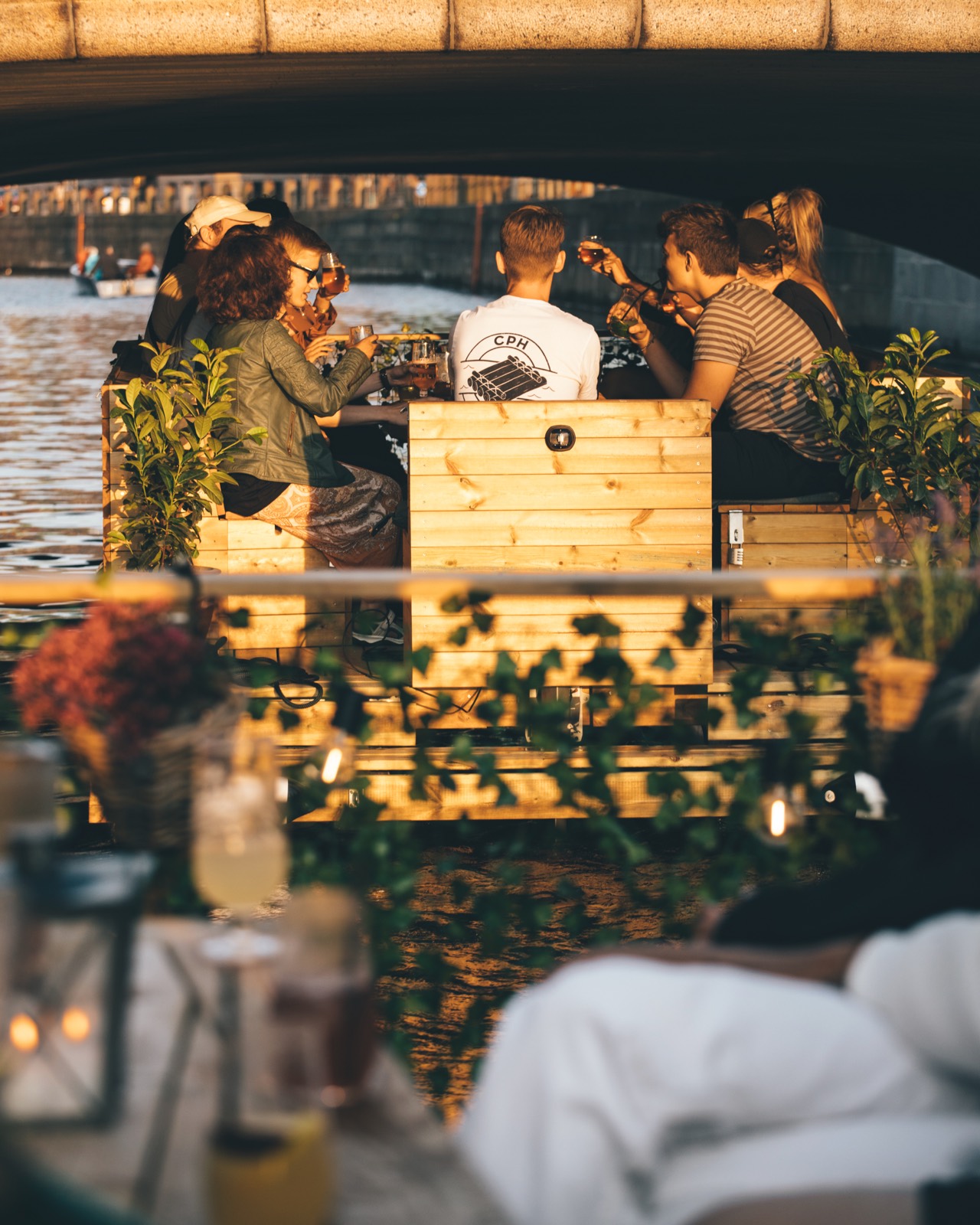 To Green Raft-tømmerflåder med planter i hegnet sejler efter hinanden under en bro