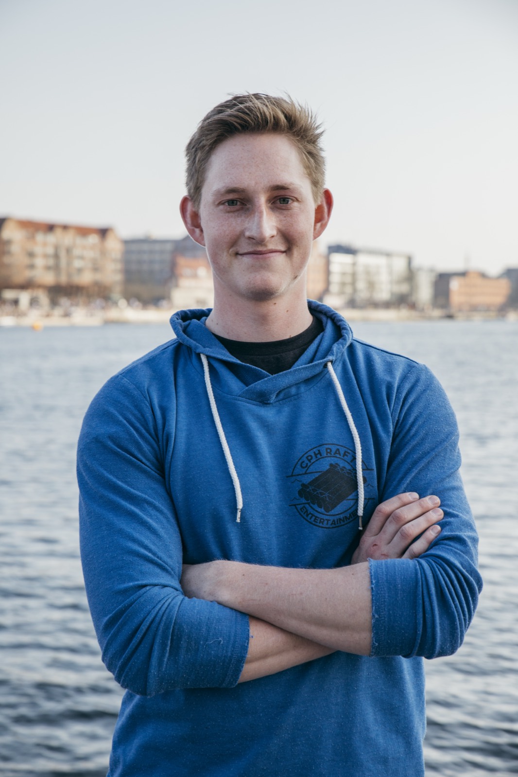 Alex Randskov i blå hættetrøje med armene over kors foran havnen