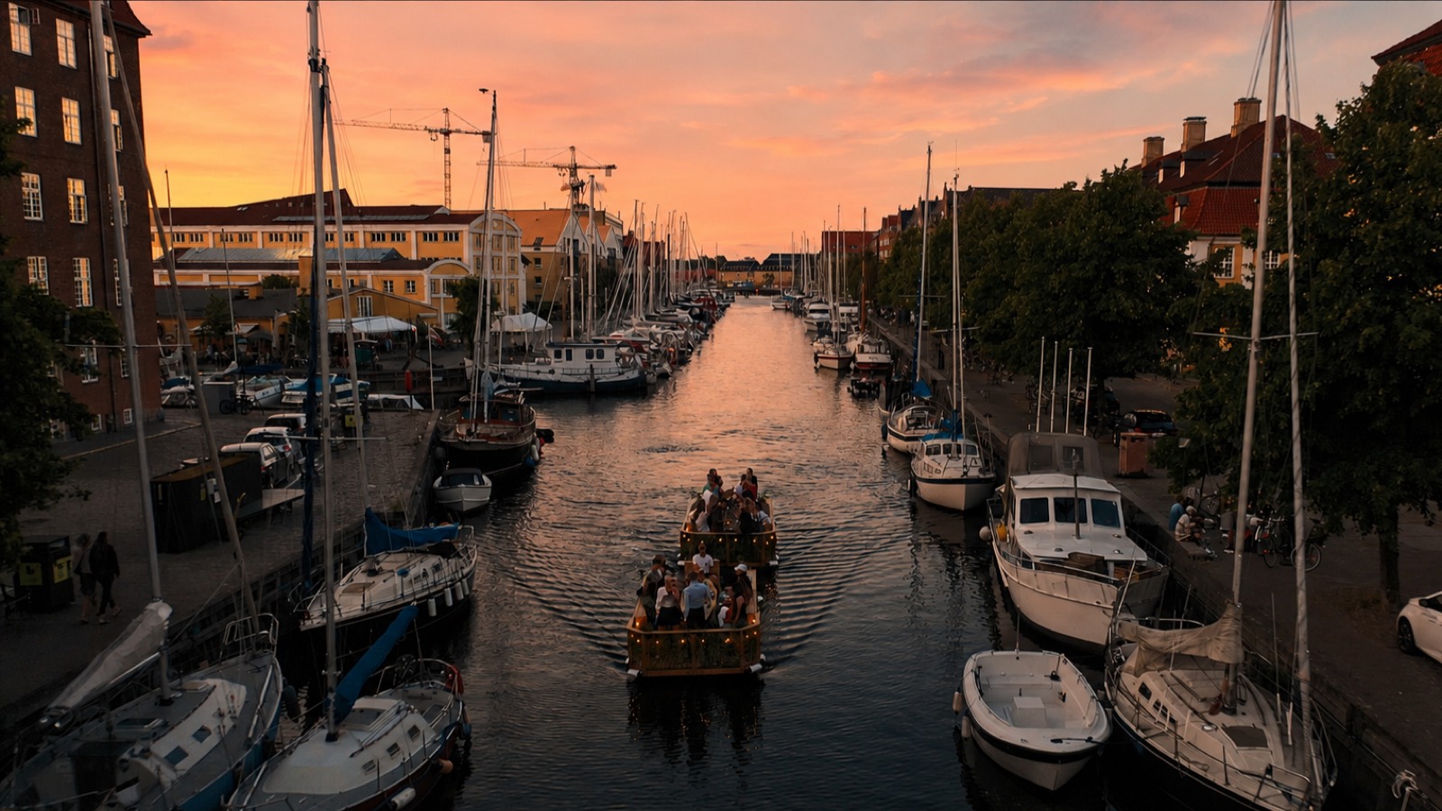 En Green Raft sejler gennem Christianshavns Kanal mellem sejlbåde i solnedgang