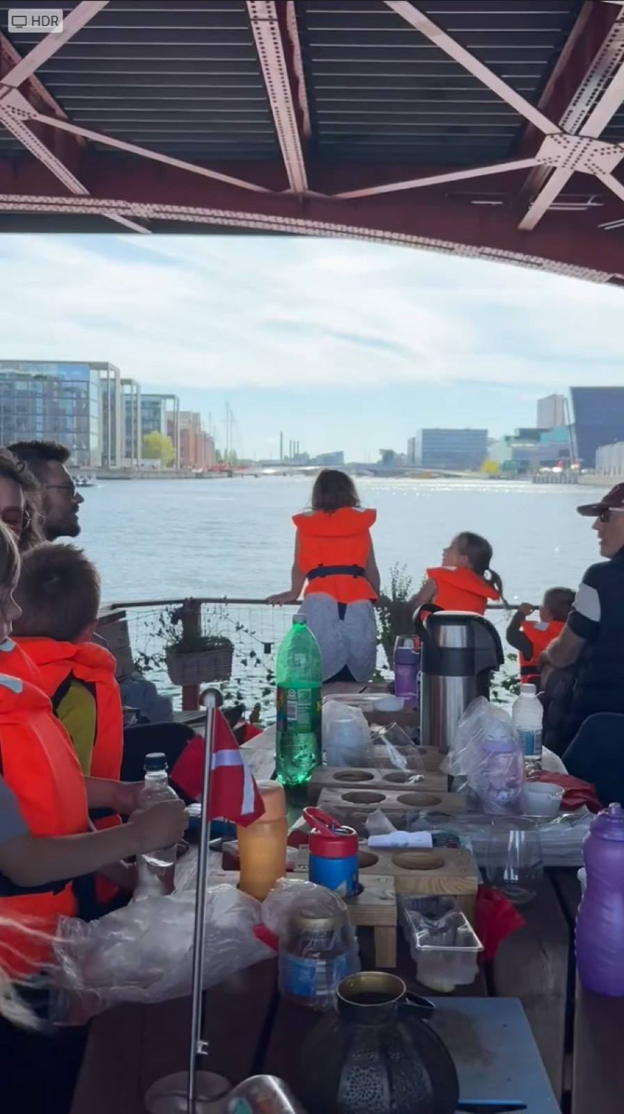 Børn i redningsveste ser ud over havnen fra forenden af en Green Raft